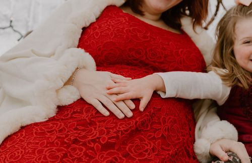Close-up of hands resting on red lace dress with white sleeve detail.