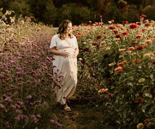 A figure stands on a garden path surrounded by red poppies and purple wildflowers at sunset.