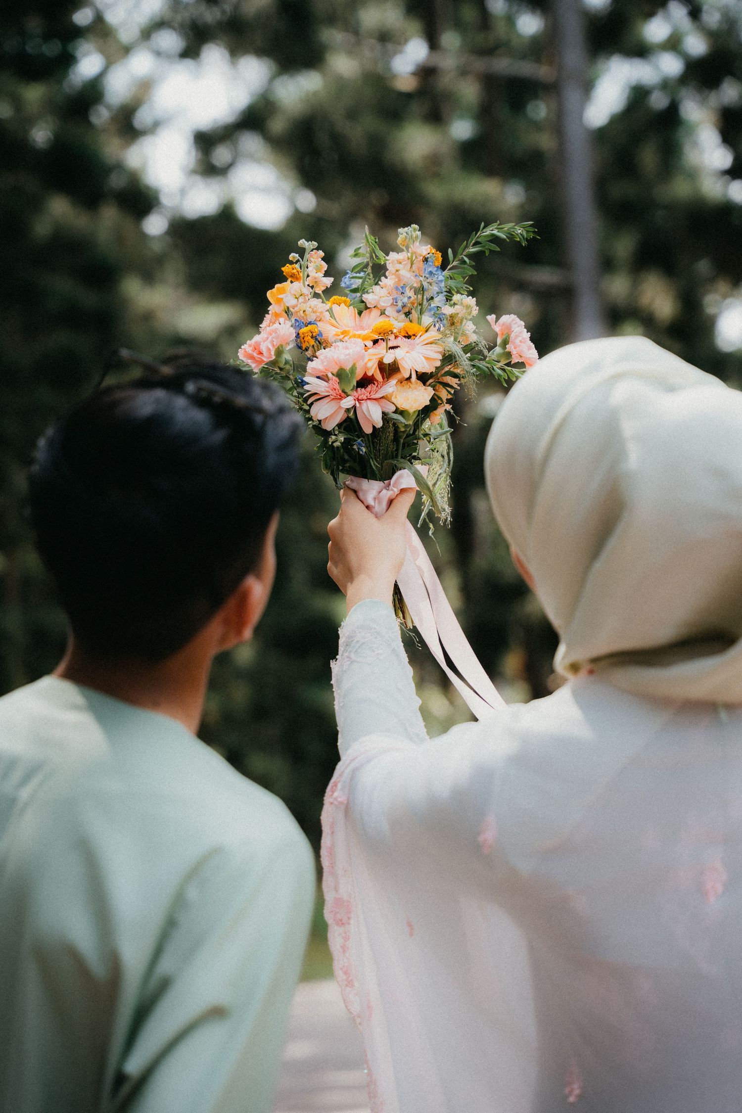 A wedding ceremony scene with soft floral arrangements and flowing white fabric in an outdoor garden setting.