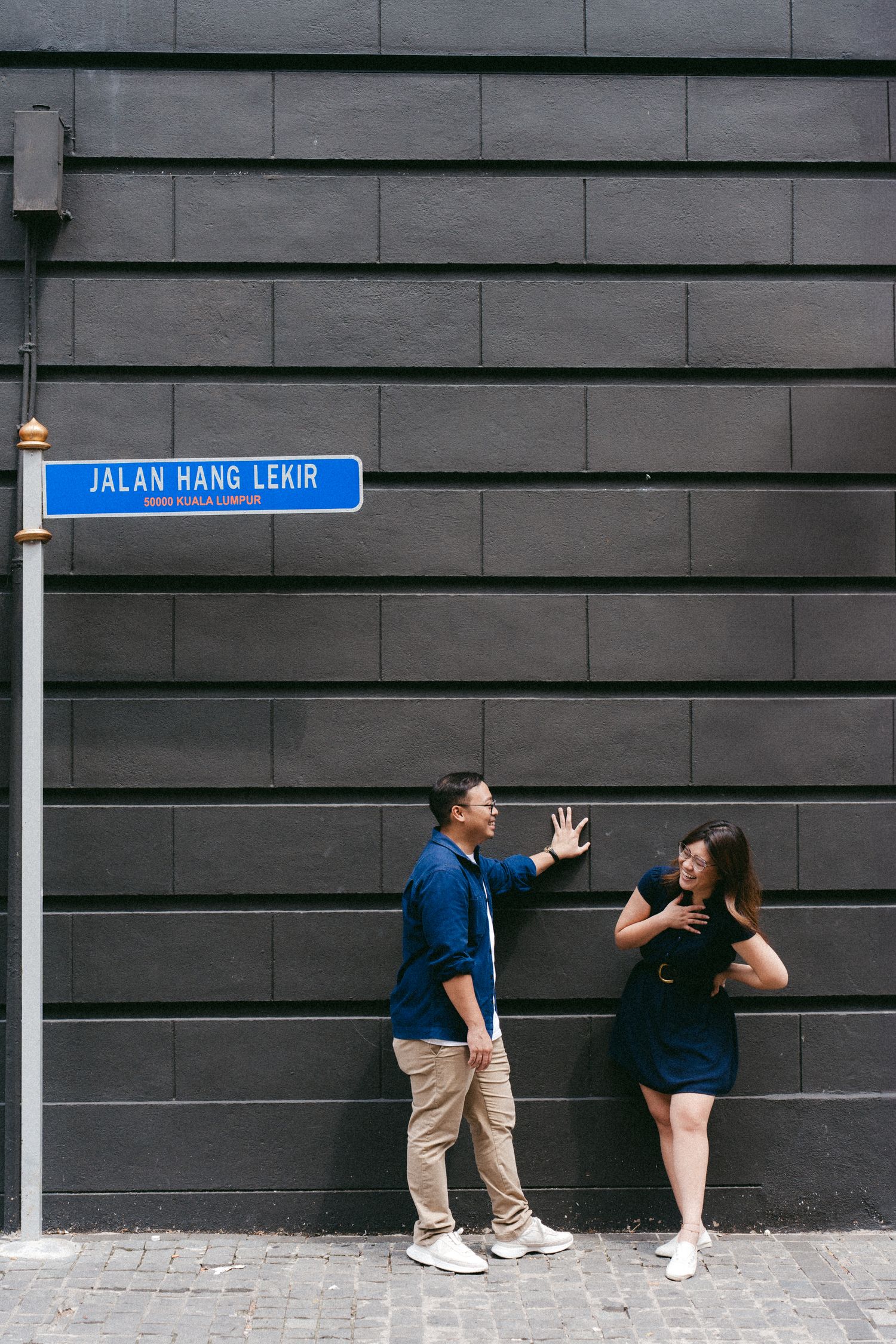 Couple in casual outfits playfully interacting against a modern gray wall in a sequential photo series.