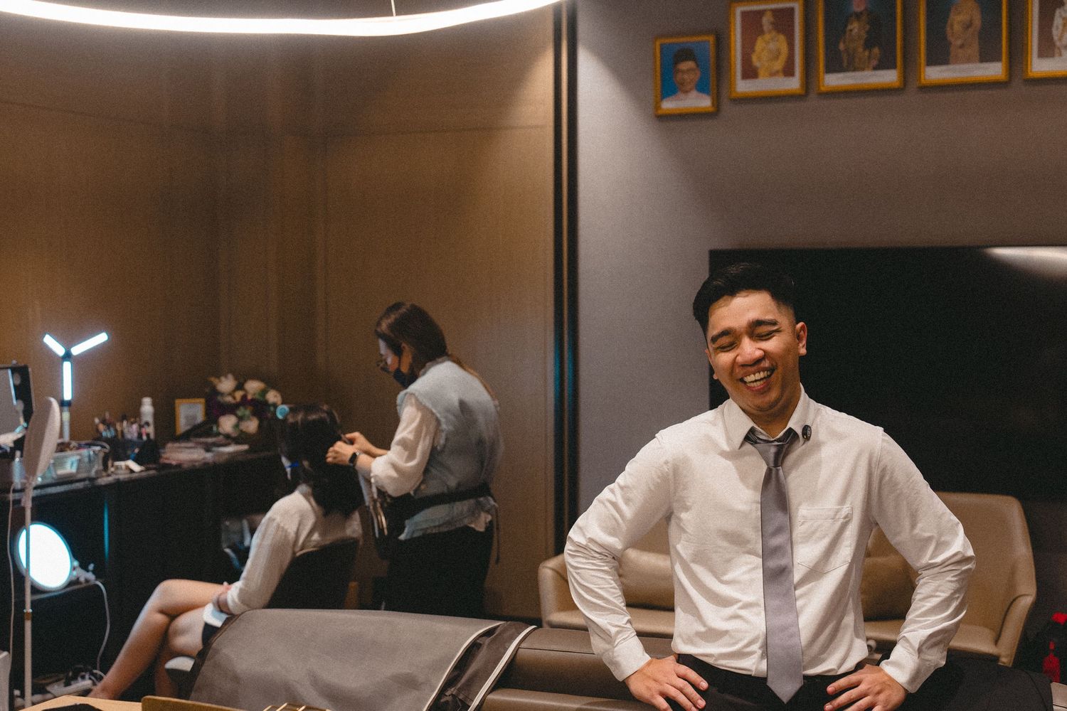 Stylish modern barbershop interior with leather chairs and framed photos on wall while professionals work with clients.