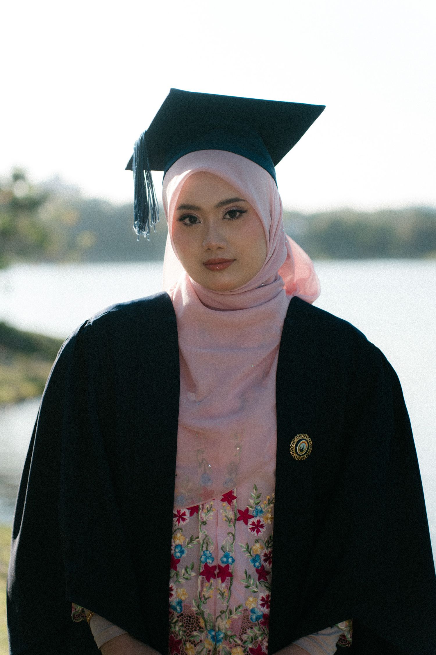 A person in a pink hijab and black blazer stands outdoors by a waterfront in a series of similar poses.