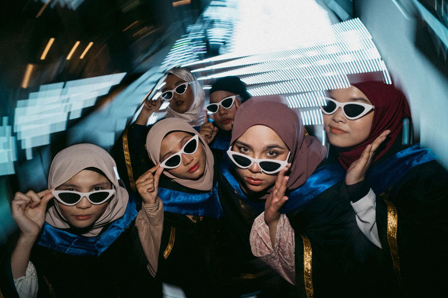 Group of graduates wearing matching white sunglasses pose for stylish photo.