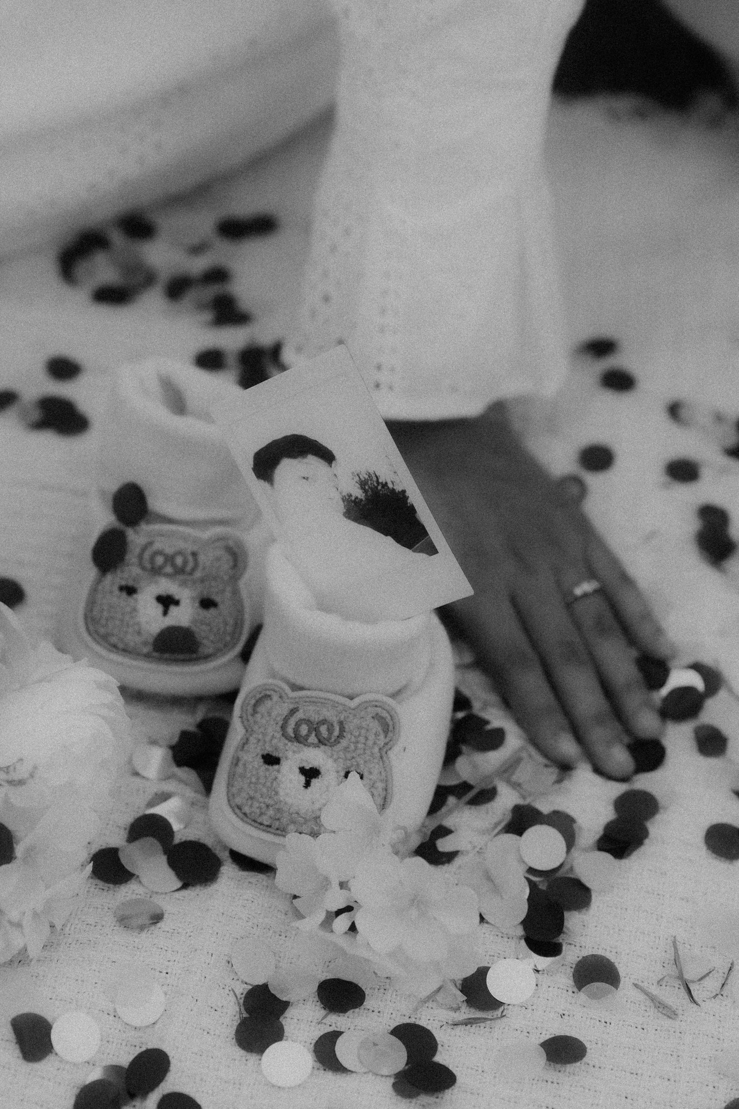 Cute bear-decorated bottles surrounded by black and white confetti on a white surface.