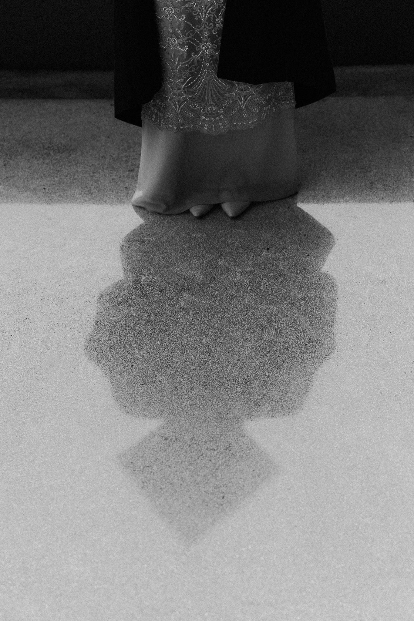 Black and white photograph of an elephant's foot and its shadow cast on sandy ground.