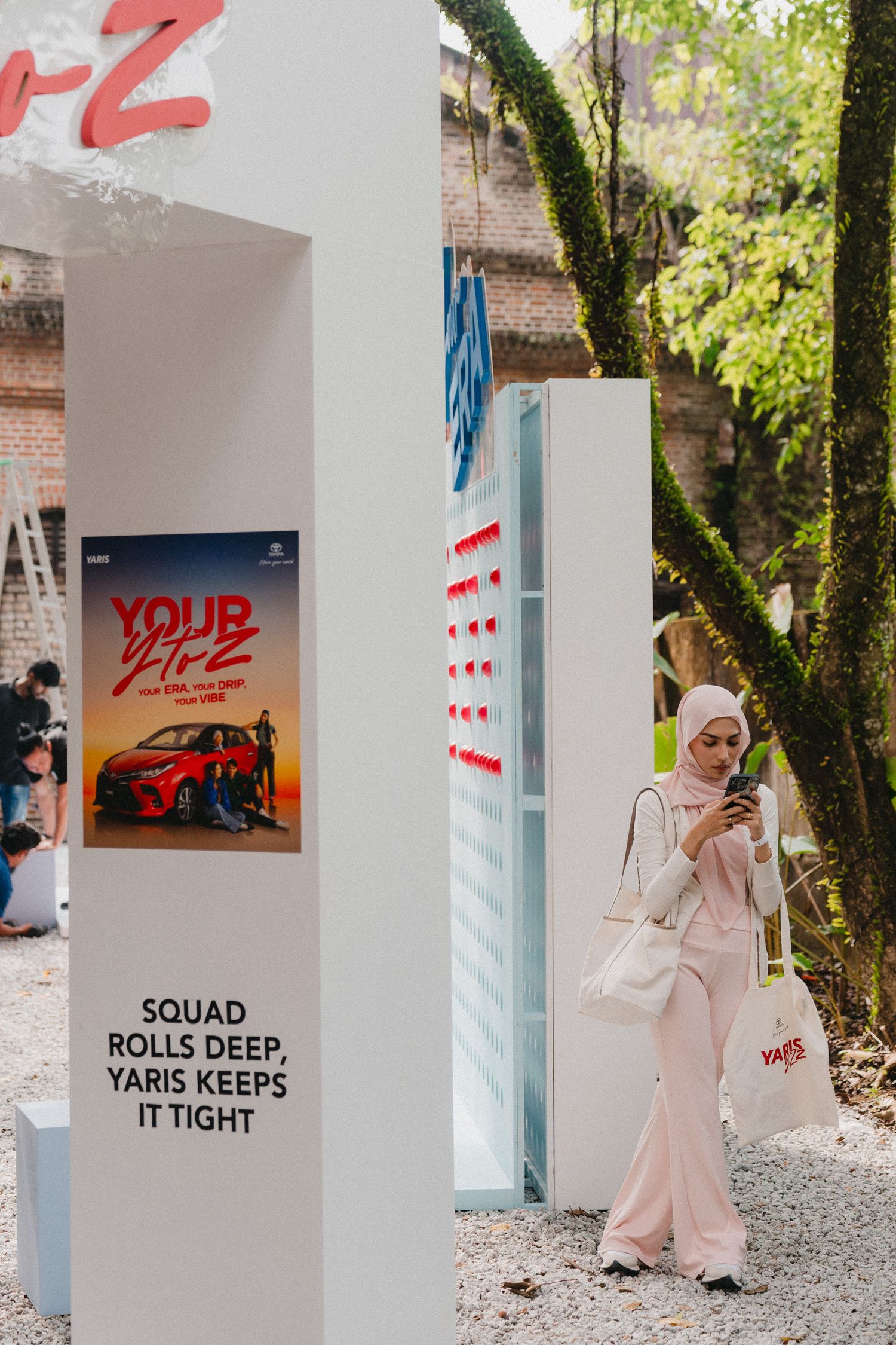 A series of outdoor art installations with white walls and red text displays in a garden setting.