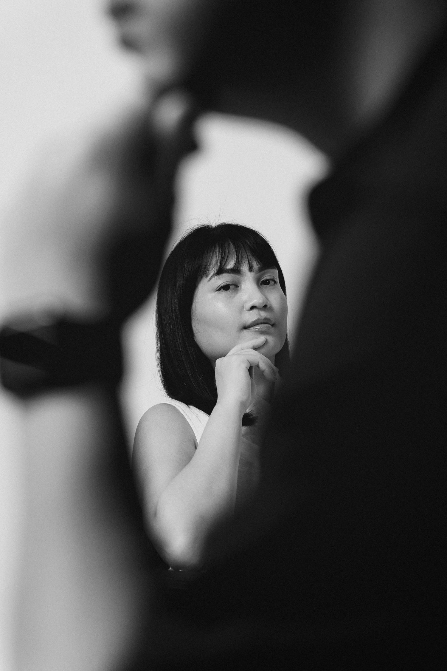 Black and white portrait showing a contemplative expression with hand on chin in dramatic lighting.