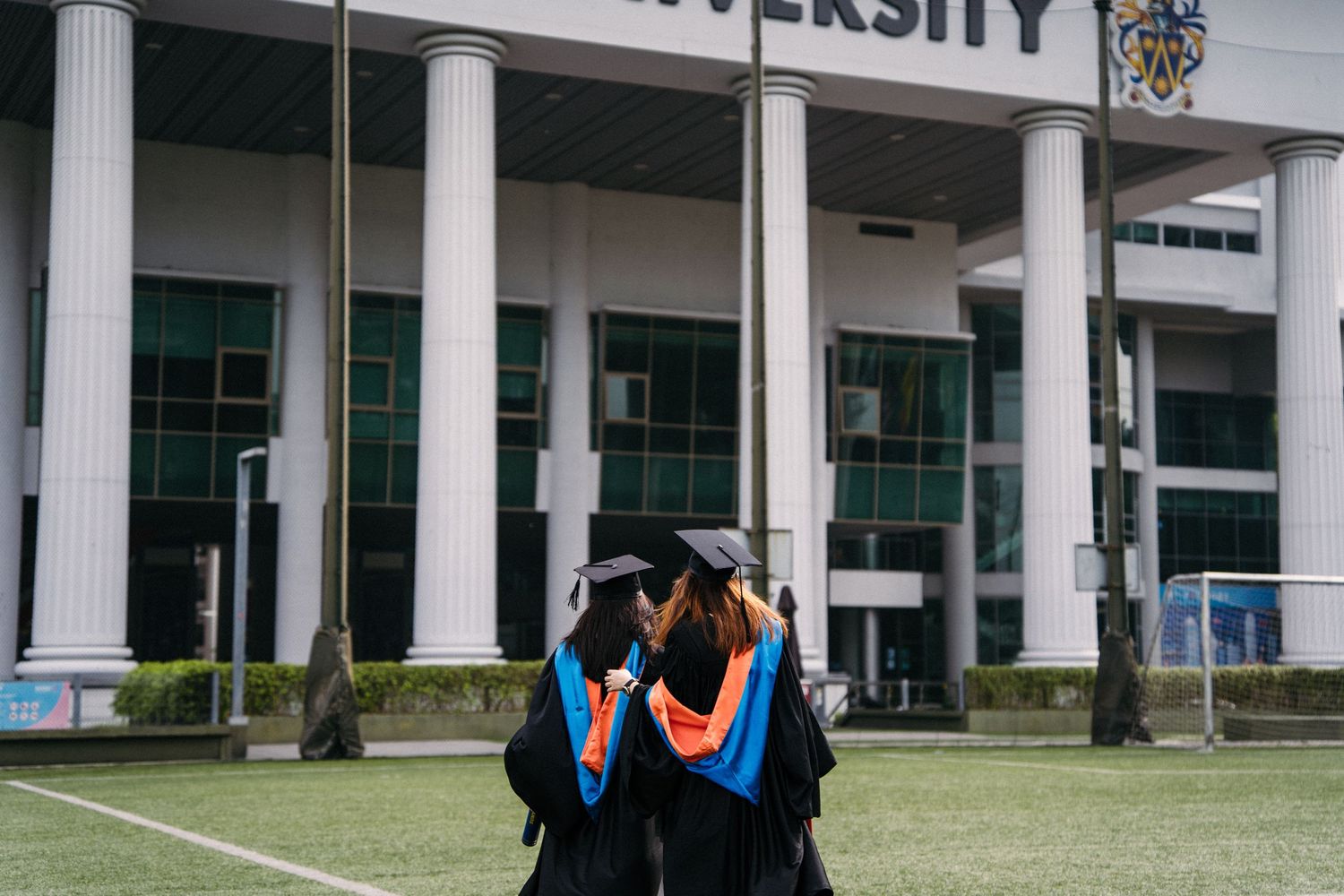 Two graduates sharing an intimate moment in front of Sunway University building entrance.