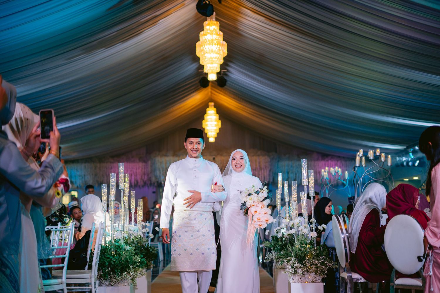 An elegant wedding ceremony in a draped tent with glowing lanterns and candlelit decor creating a romantic atmosphere.