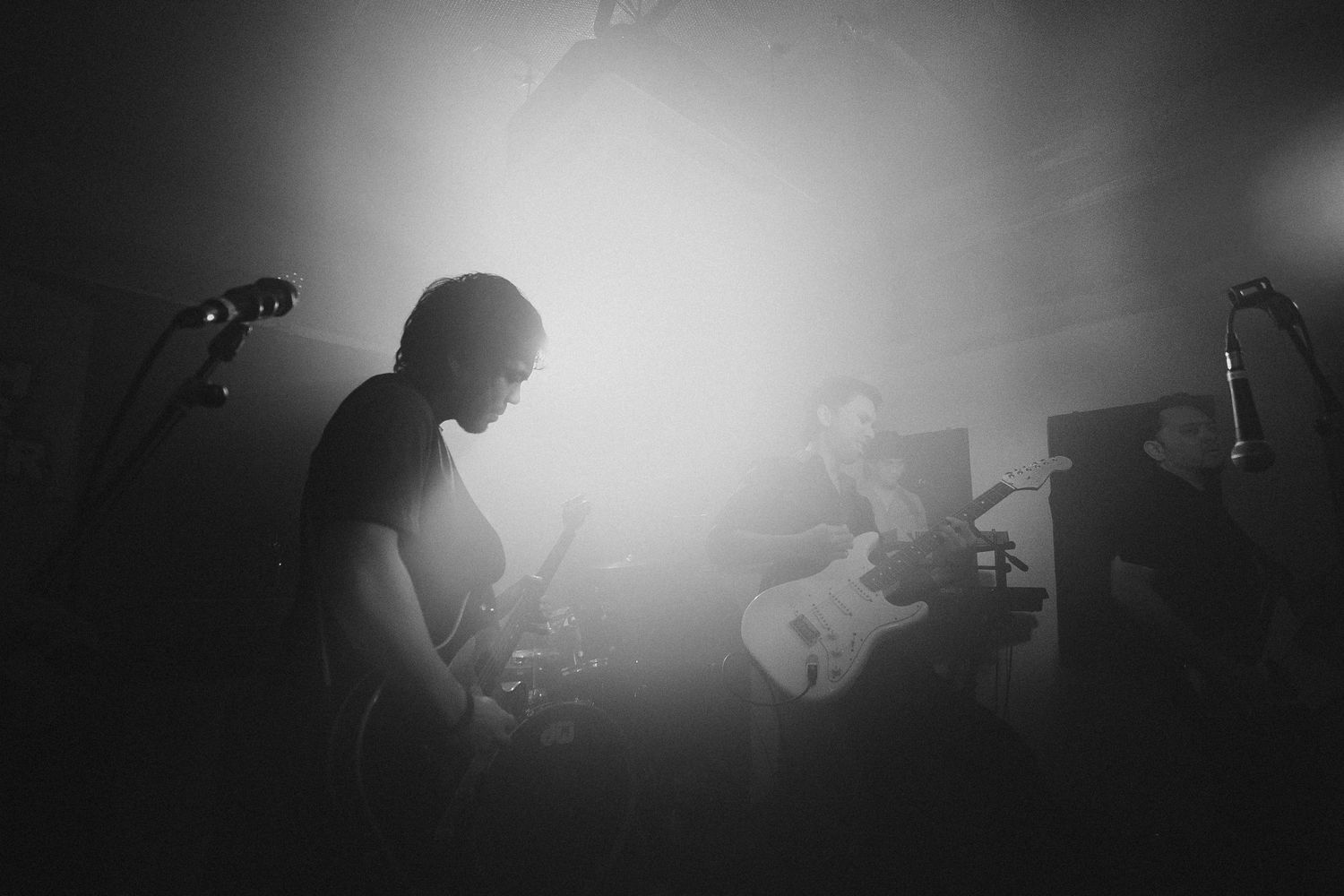 Silhouetted musicians performing on stage with bright backlighting creating dramatic atmospheric effect.