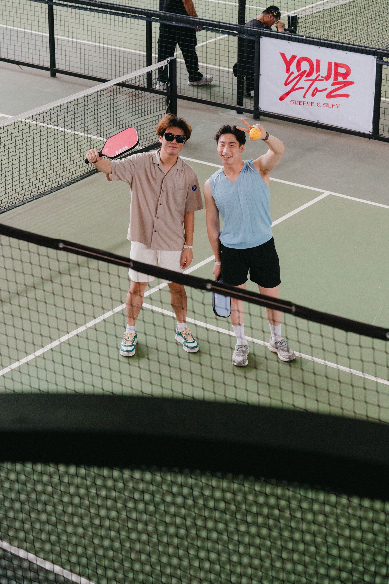 Two people playing pickleball on an indoor court with a net dividing the space between them.