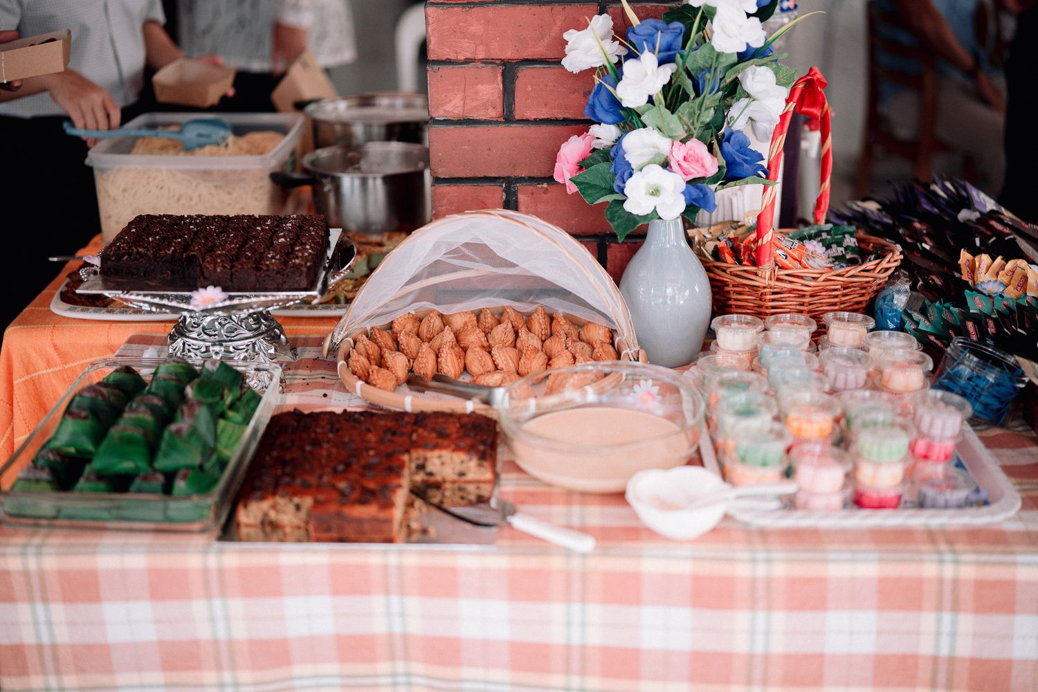 A festive buffet table with assorted desserts, pastries, and colorful treats, decorated with a floral centerpiece.
