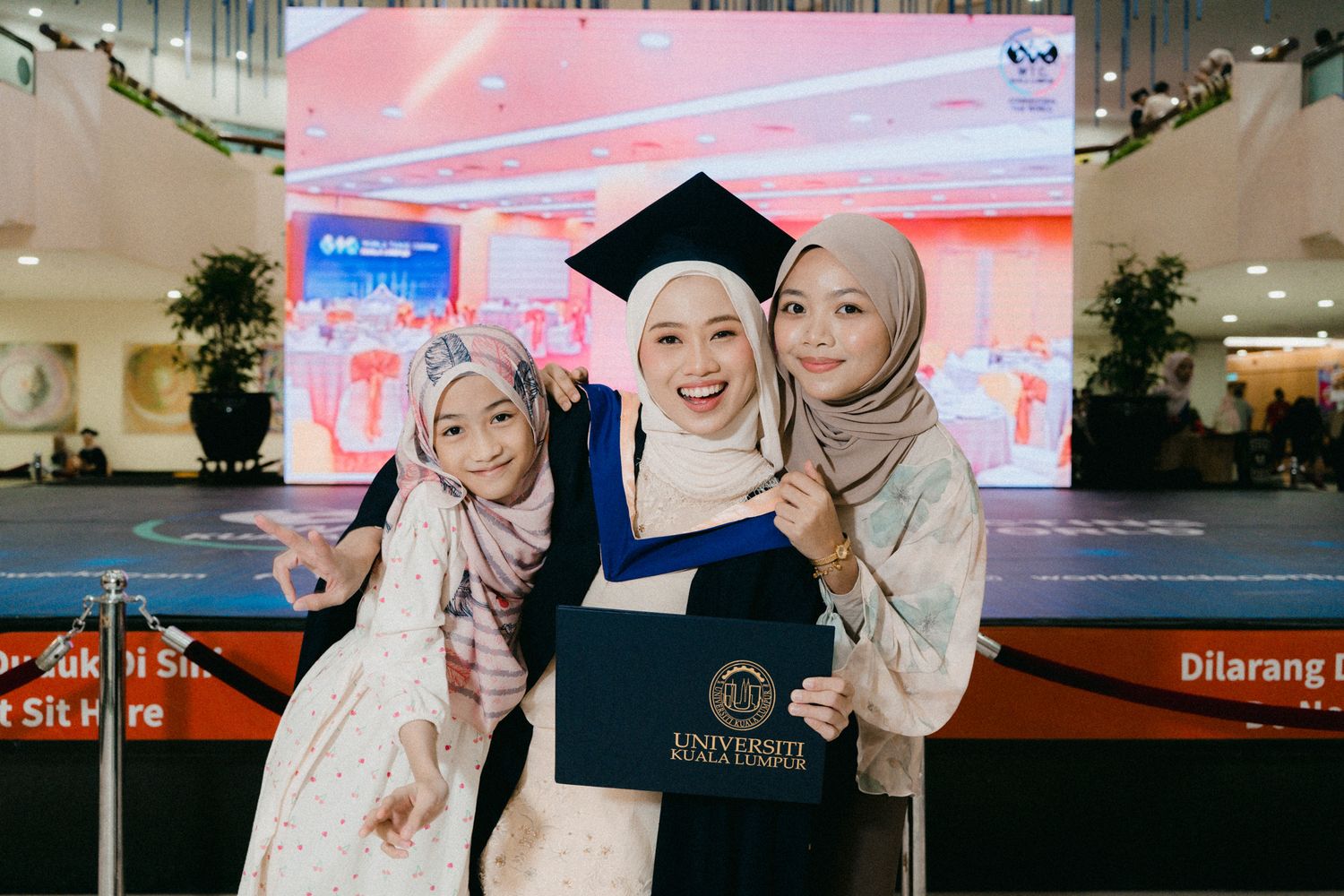 A group wearing matching light-colored hijabs and outfits pose together in a modern retail setting.