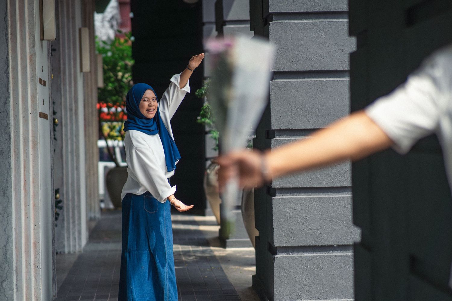 Motion blur photograph of person in blue dress waving on urban street.