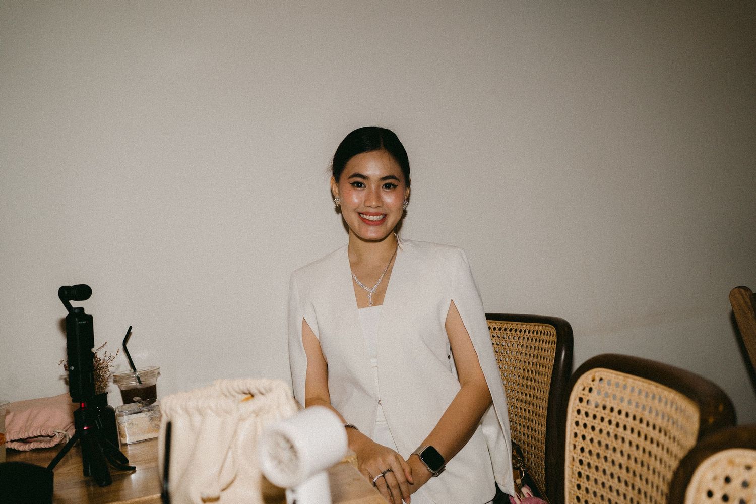 Person in professional white attire seated in a chair indoors.
