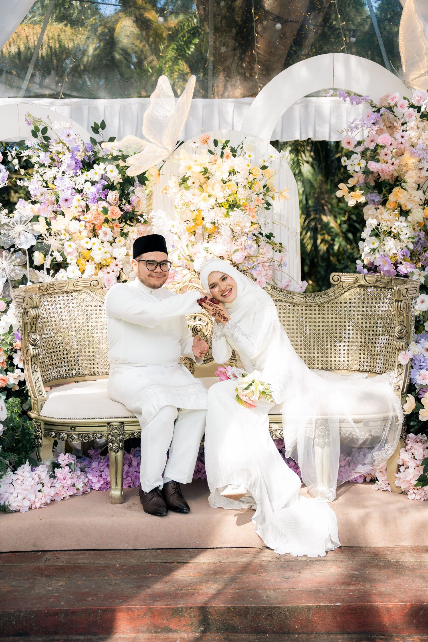 Elegant wedding setup with ornate chairs and lush floral arrangements in white, pink and yellow against a romantic backdrop.
