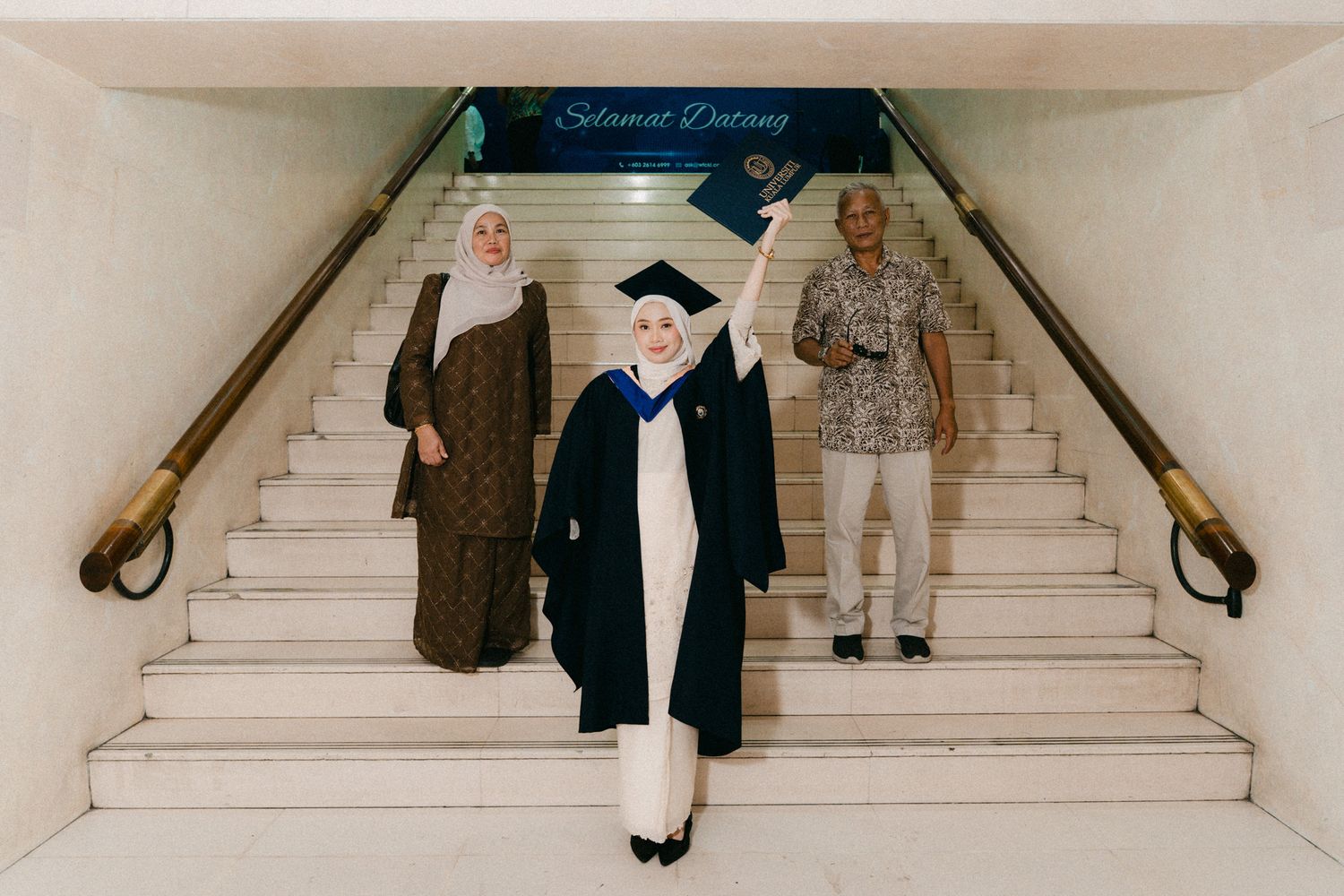 Graduate students walking up marble stairs in academic regalia during commencement ceremony.