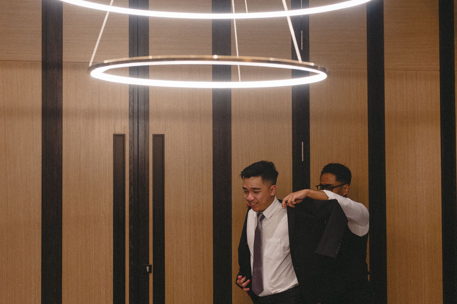 Modern elevator interior with circular LED light fixtures and wood-paneled walls.