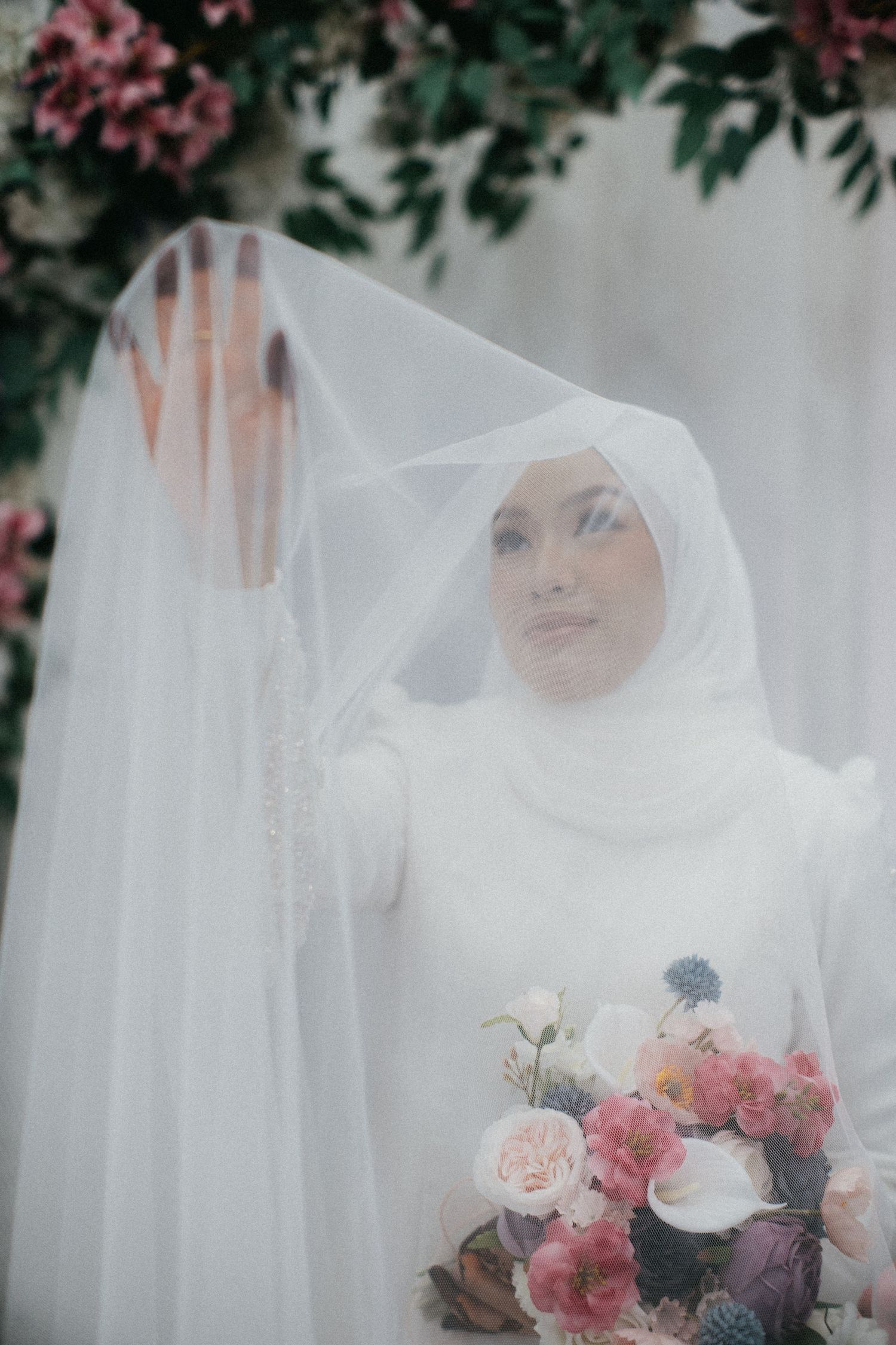 A romantic bridal portrait series with sheer white veil and pink floral bouquet in a dreamy garden setting.