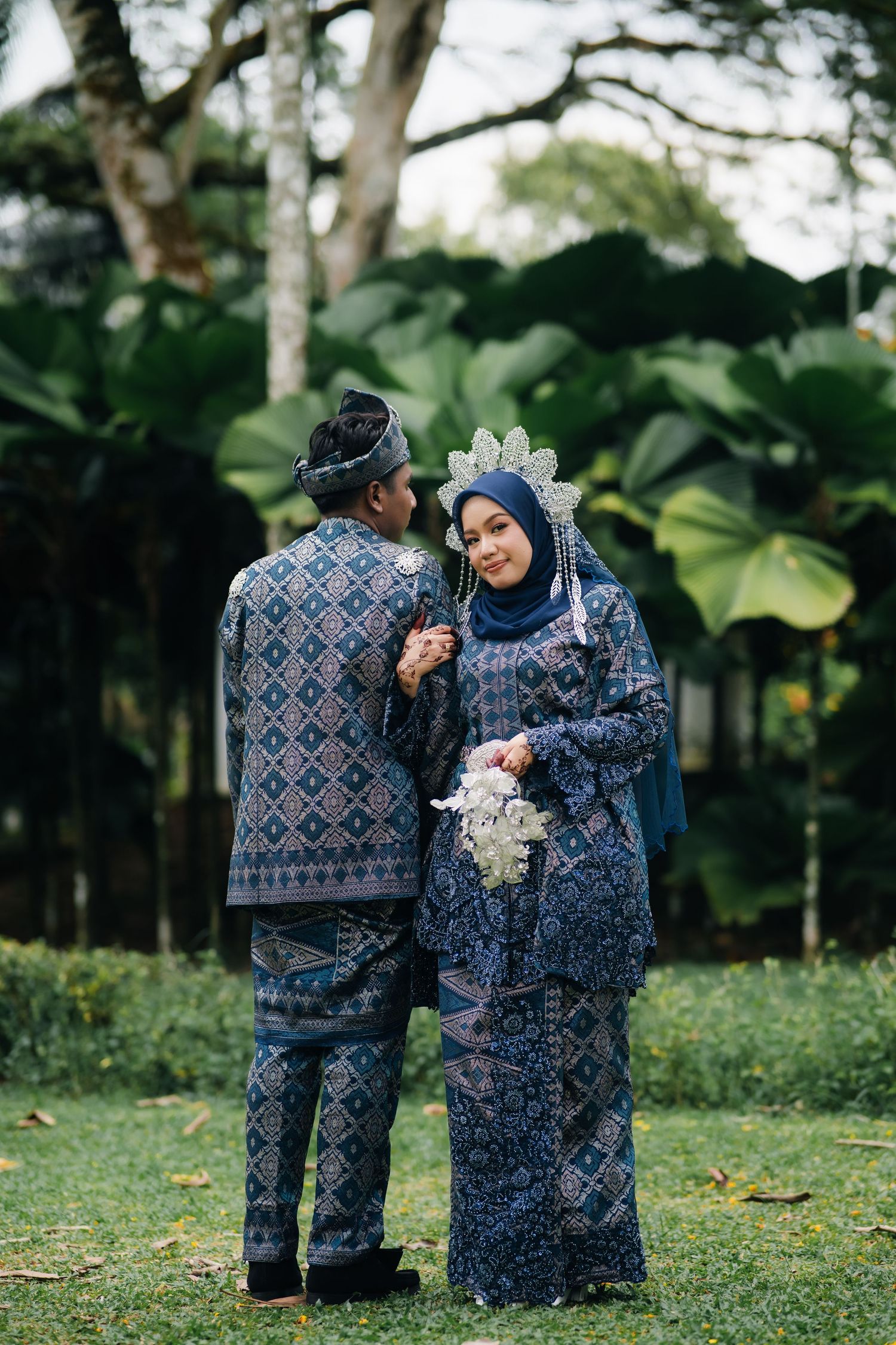 A couple wearing matching blue patterned sweaters poses together in a garden setting across multiple candid shots.