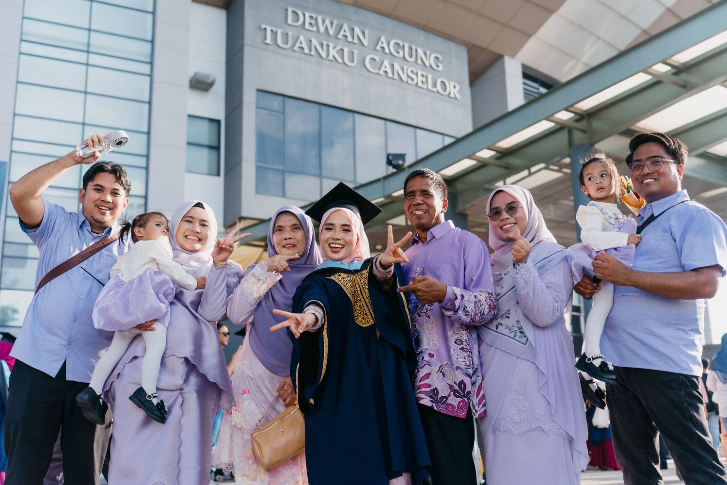 A group of medical professionals in white coats and hijabs gather outside a building entrance.