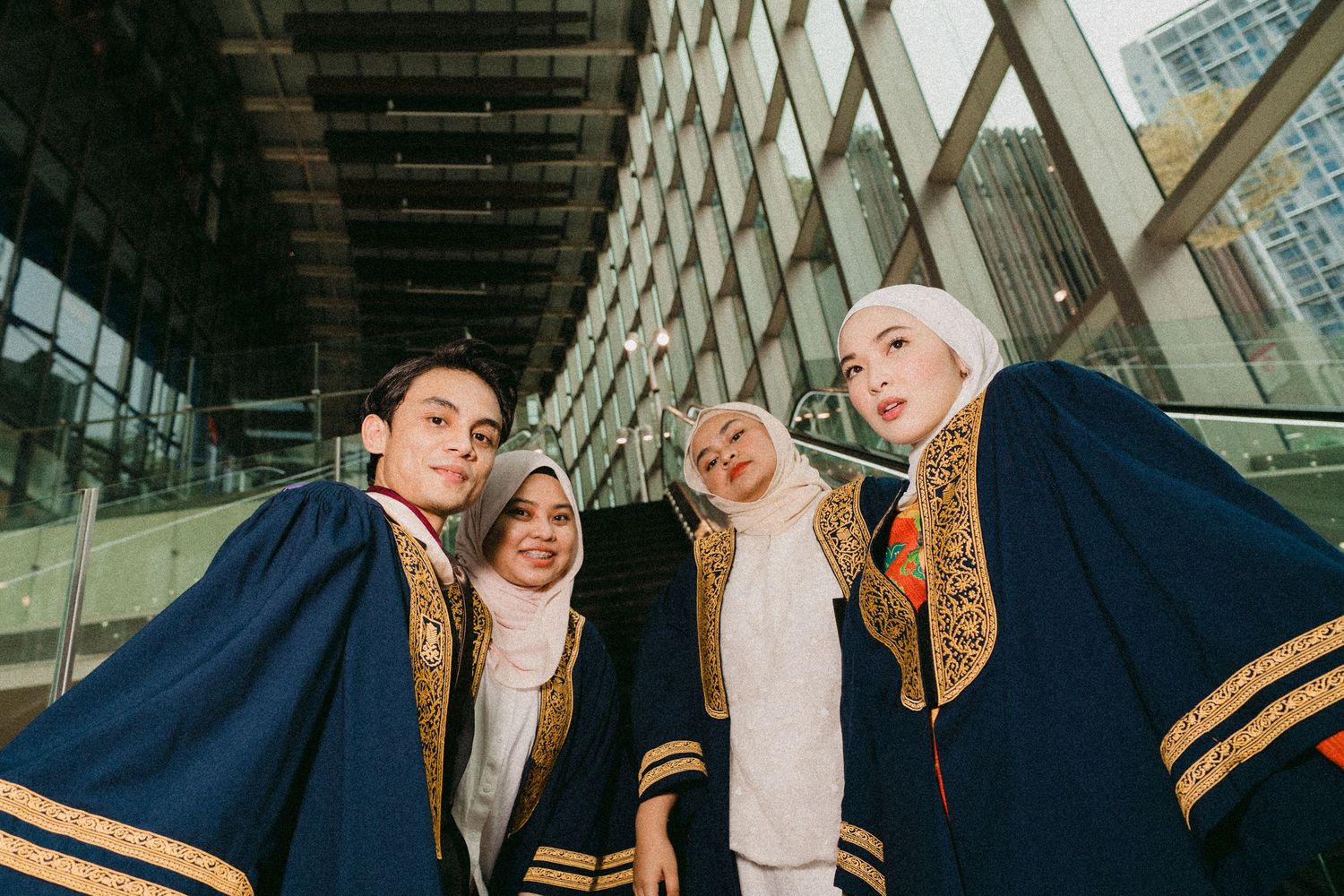 Students in graduation gowns pose together under modern architecture.