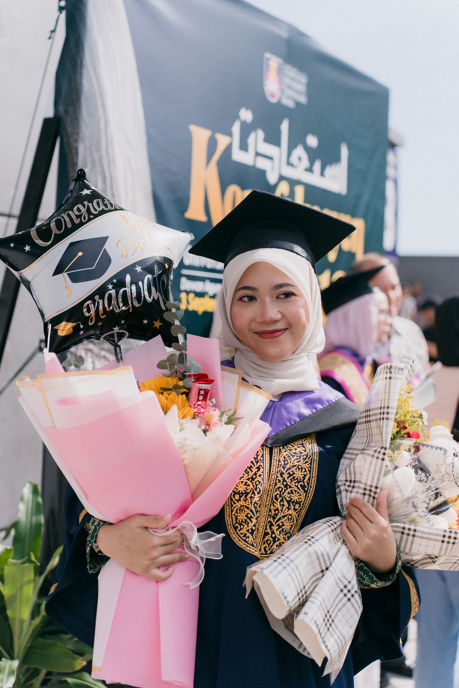 A group wearing graduation caps and holding pink bouquets at a graduation celebration event.