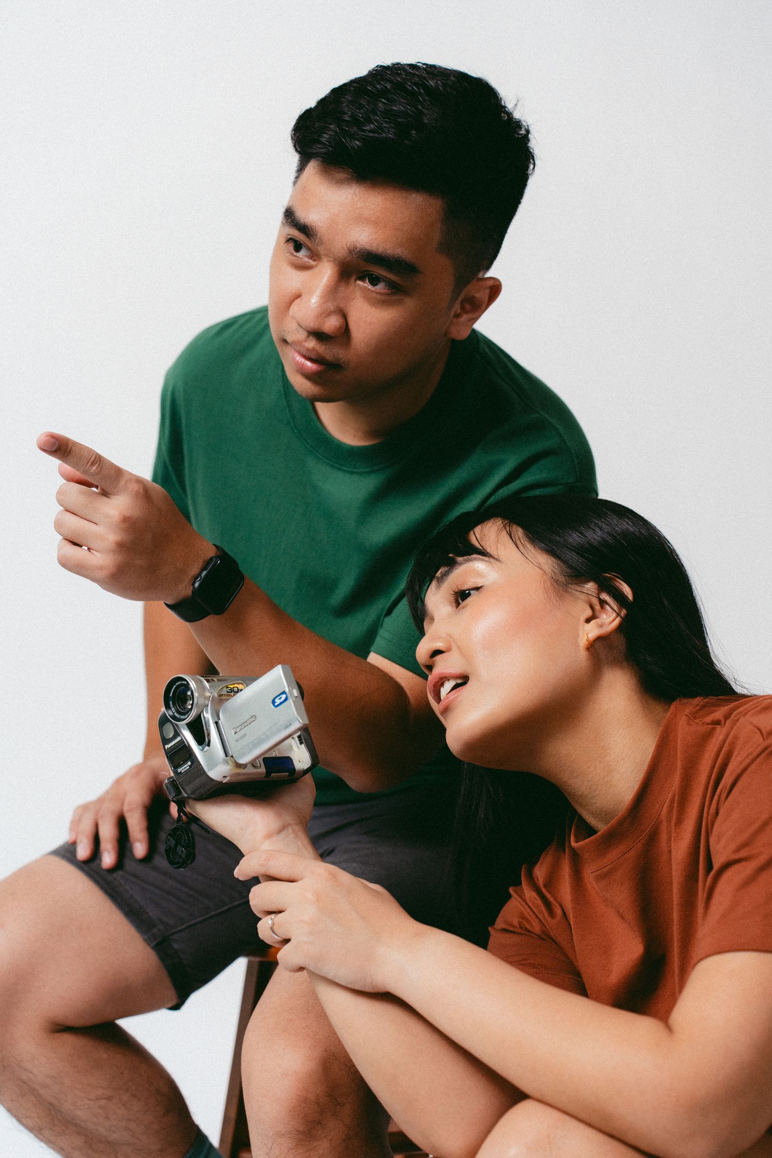 Couple examining vintage camcorder while sitting together in studio setting.