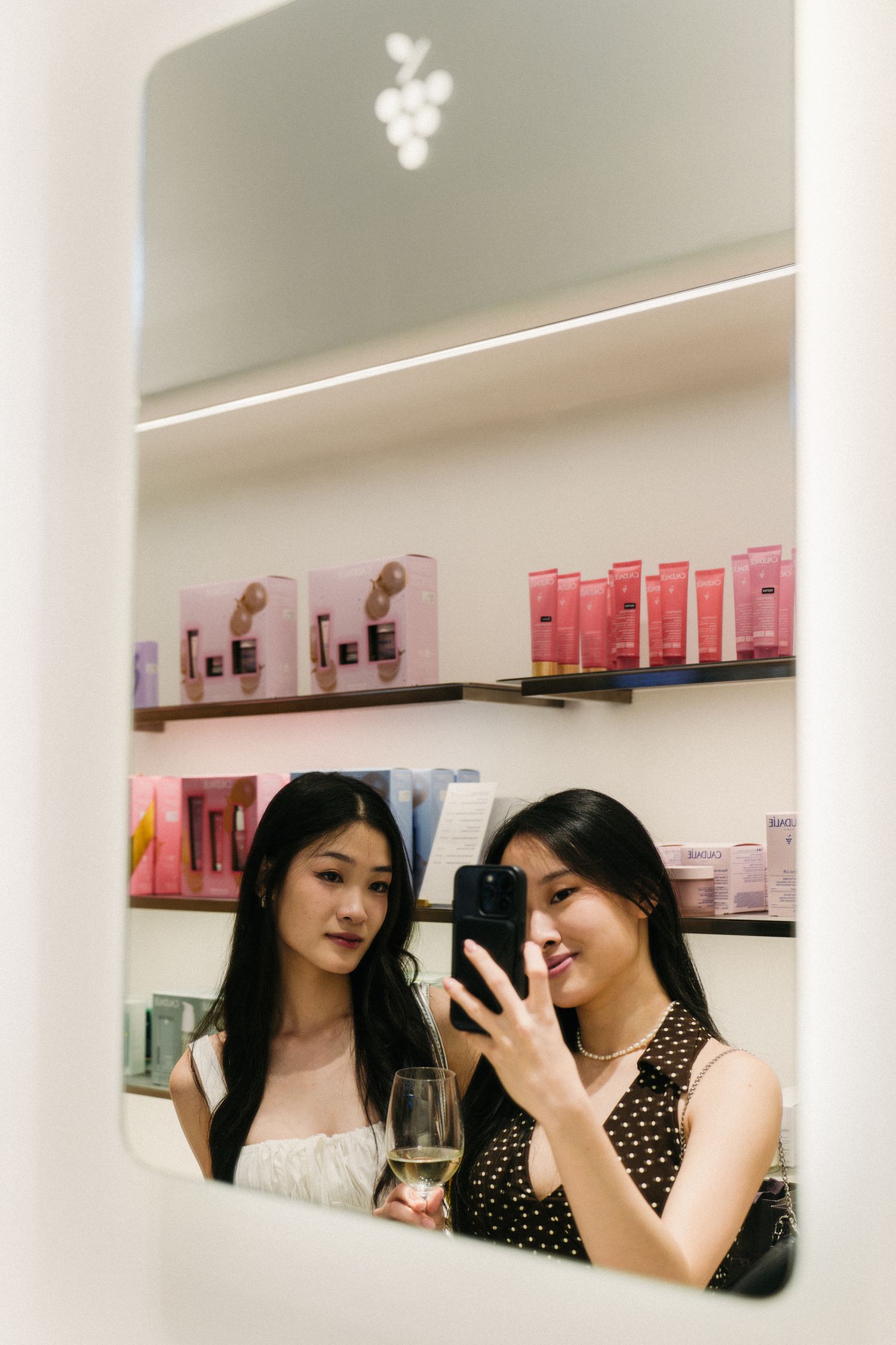Beauty product display with pink packaging reflected in a mirror.