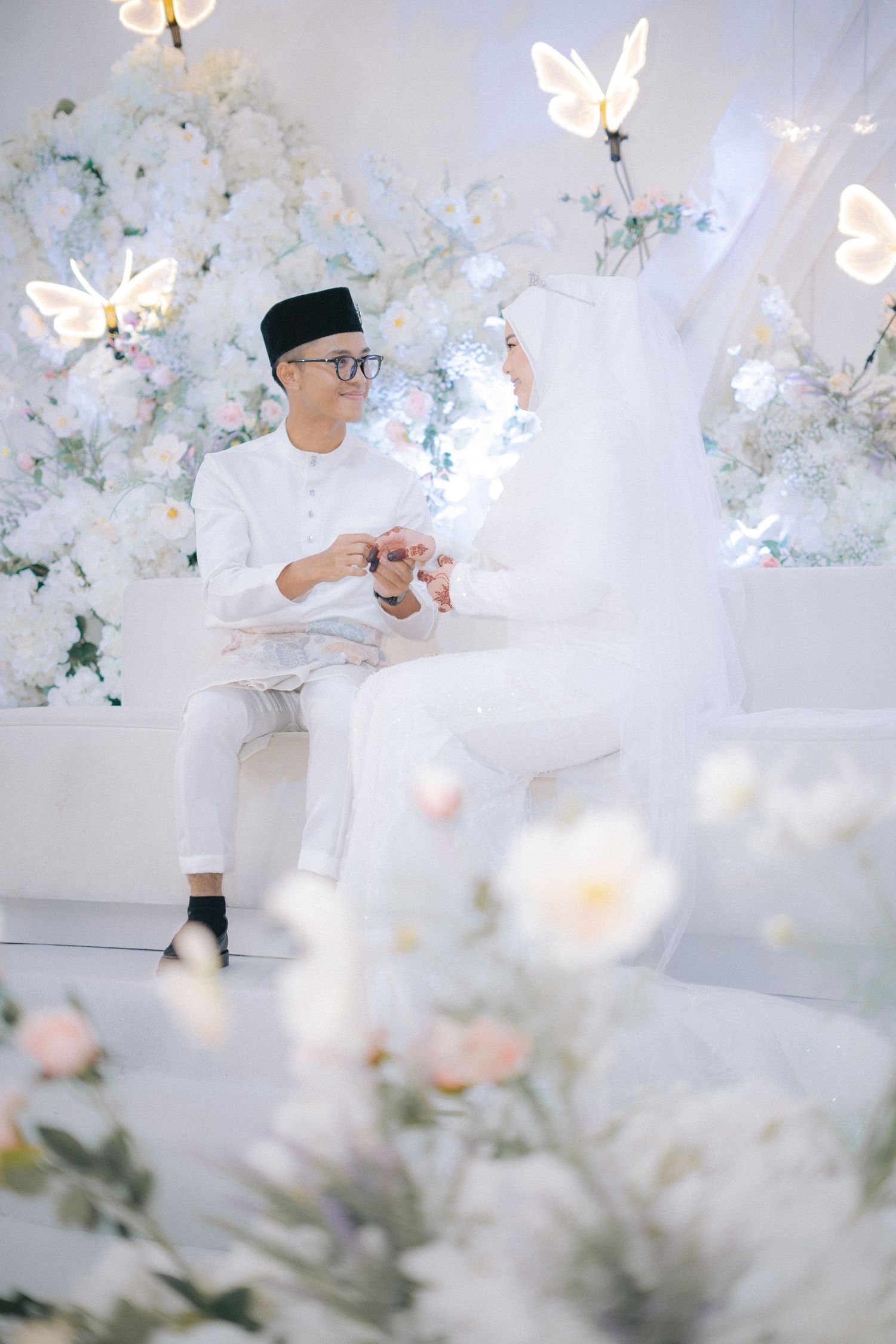 Soft dreamy portraits with white floral decorations and butterfly light effects in a bright studio setting.