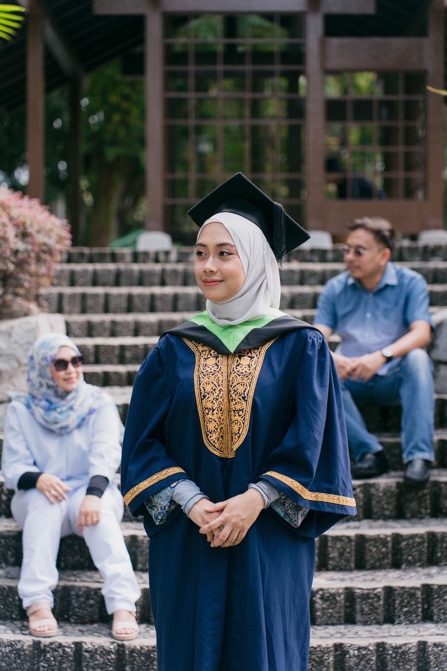 A series of graduation photos showing someone in a navy blue academic gown with gold embroidery on stone steps outdoors.