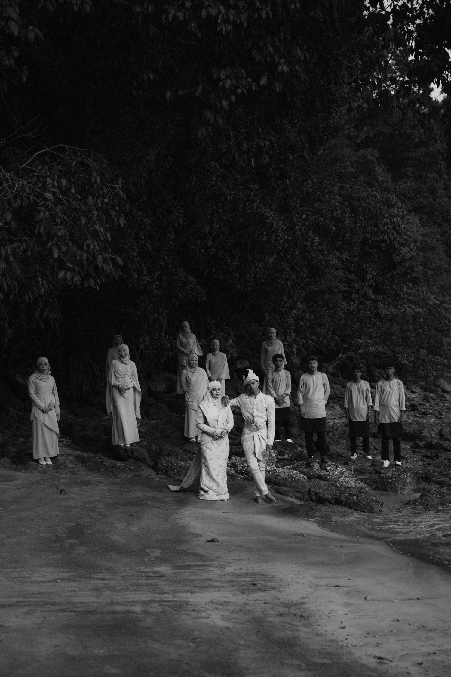 A black and white photo sequence showing people in white robes walking in a line along a dark wooded path.