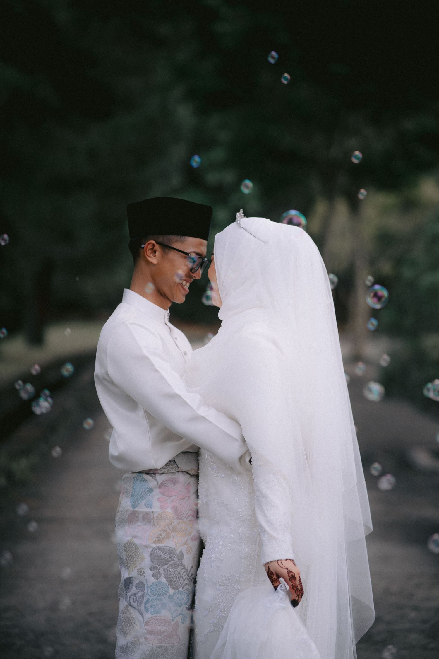 A dreamy outdoor wedding scene with floating bubbles and flowing white garments against a dark forest background.