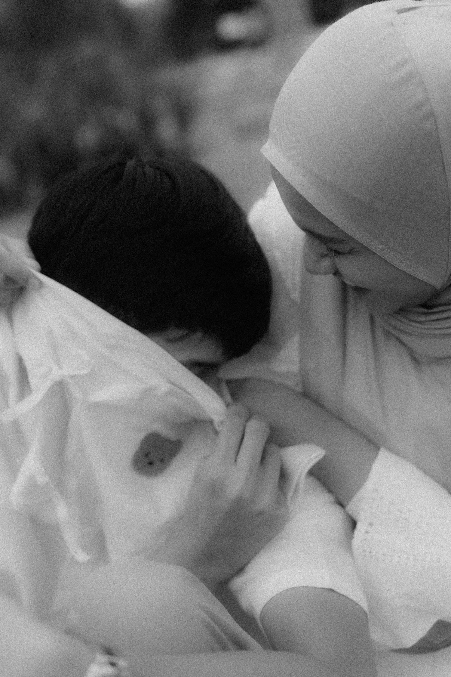 An intimate black and white photograph showing affection between two people wearing white.
