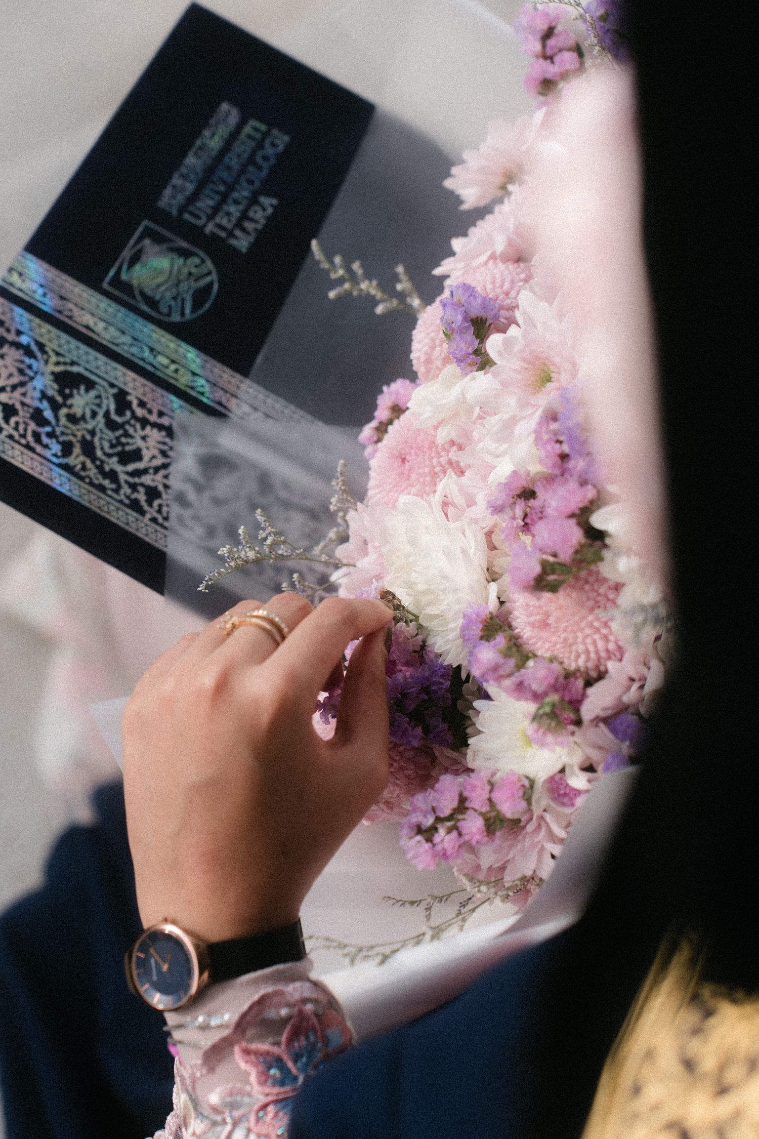 Delicate pink and purple flowers being held against a dark background with a Starbucks cup visible in frame.