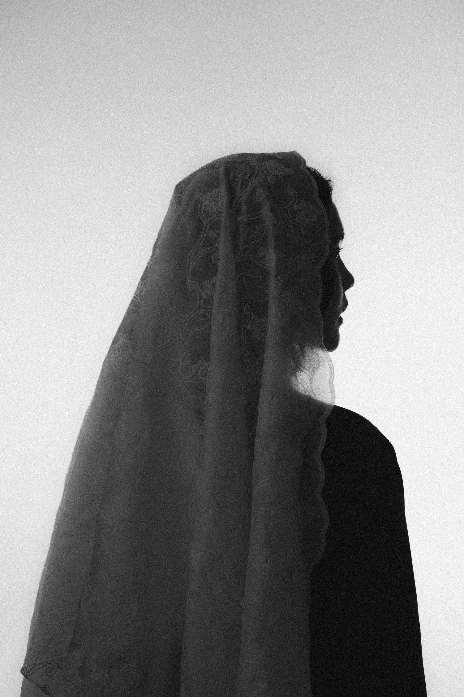 Dramatic black and white silhouette of a figure wearing a flowing dark veil.