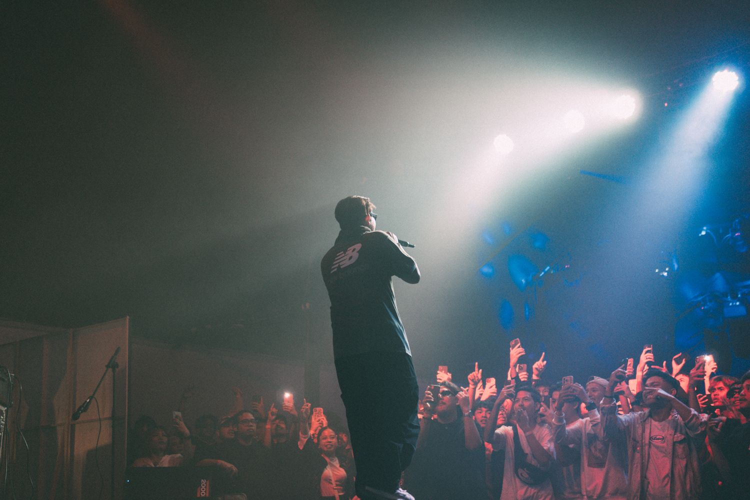 Dramatic concert performance with performer silhouetted against stage lights.