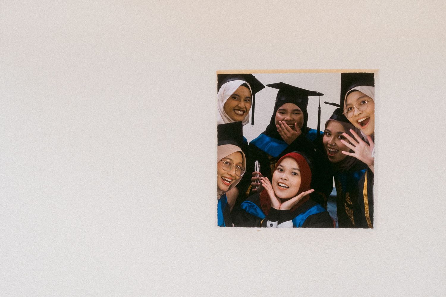 Group of graduates in caps and gowns pose together for celebratory selfie photo.