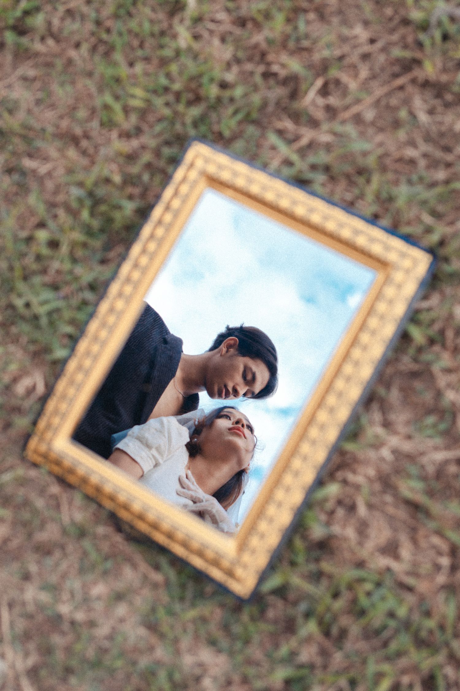 Creative wedding photo reflected in vintage frame placed on grass.
