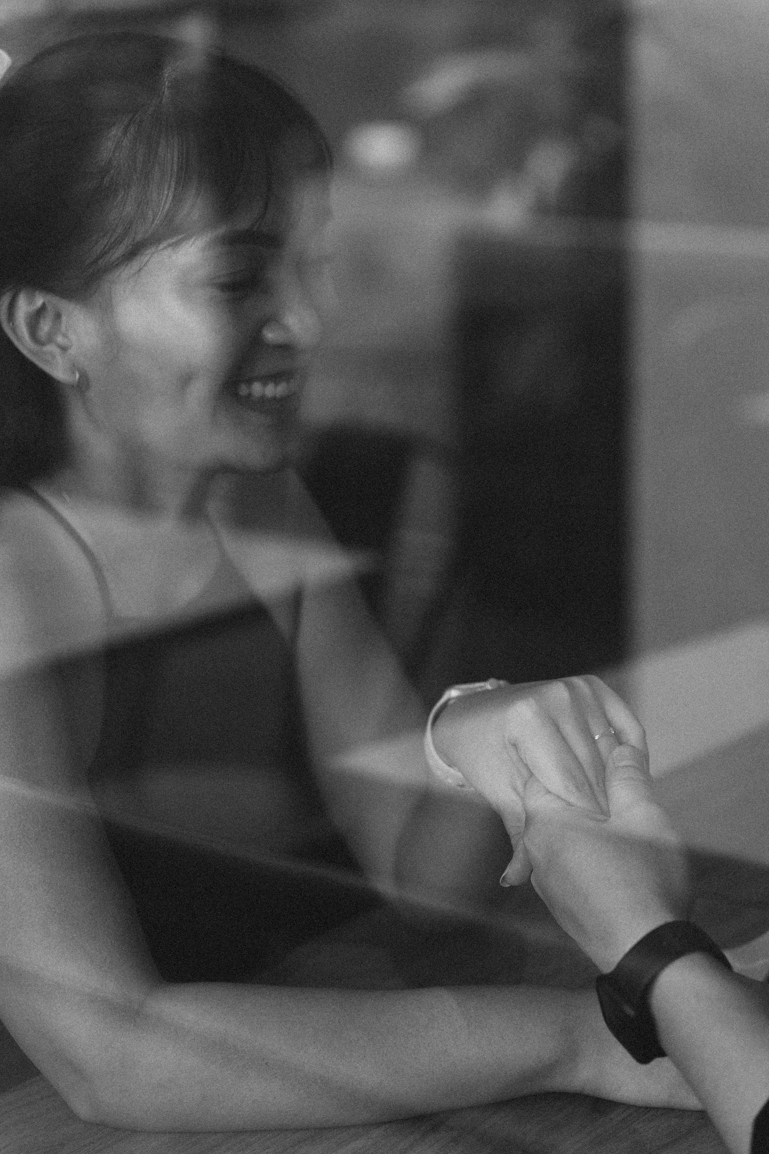 Black and white close-up through window showing hands joining together.