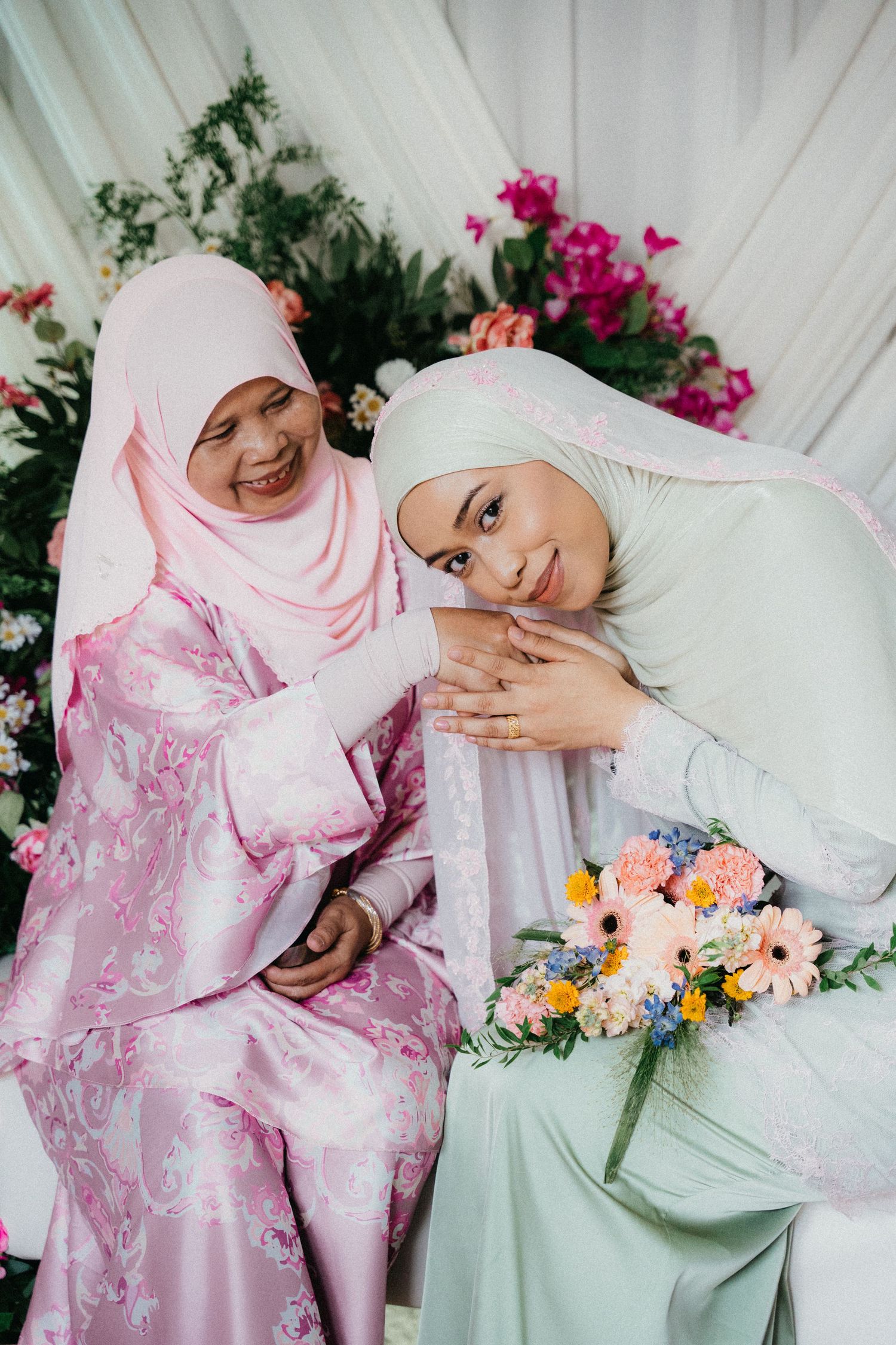 A photo collage showing someone in pink floral traditional dress posing gracefully with colorful flowers against a white backdrop.