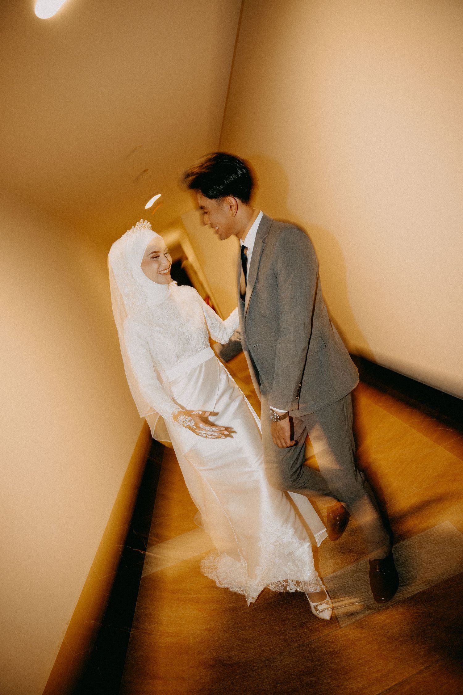 A romantic wedding photo featuring a couple in traditional wedding attire sharing a tender moment on hardwood floors.