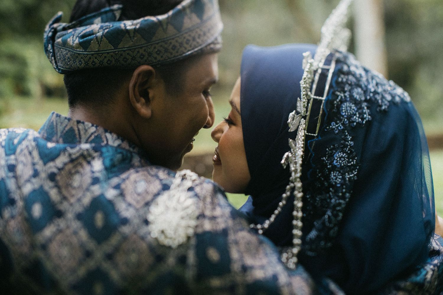 A romantic couple in traditional Nigerian attire share an intimate moment while wearing matching blue and silver patterns.