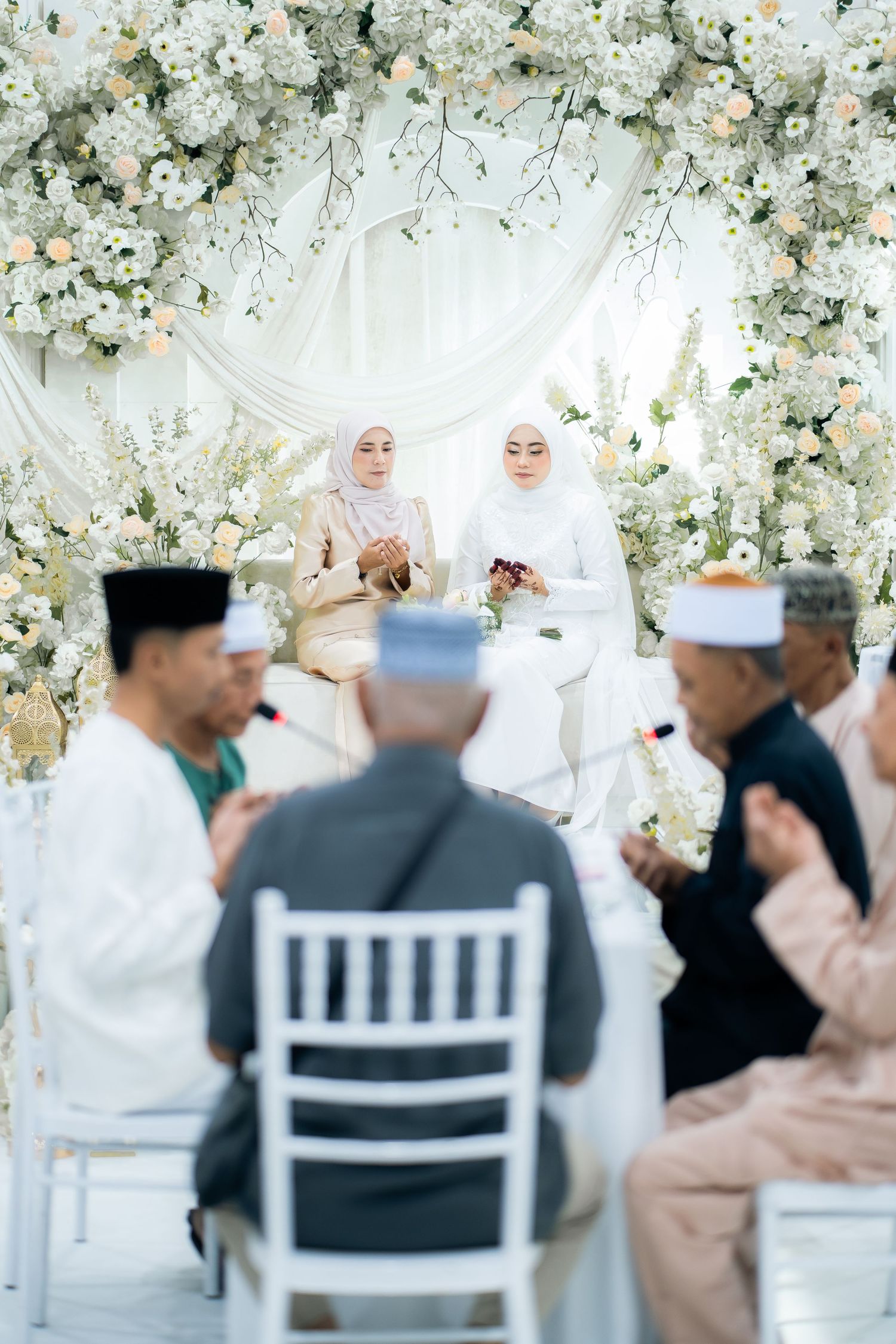 A traditional wedding ceremony with decorative white floral arrangements and guests seated during the celebration.
