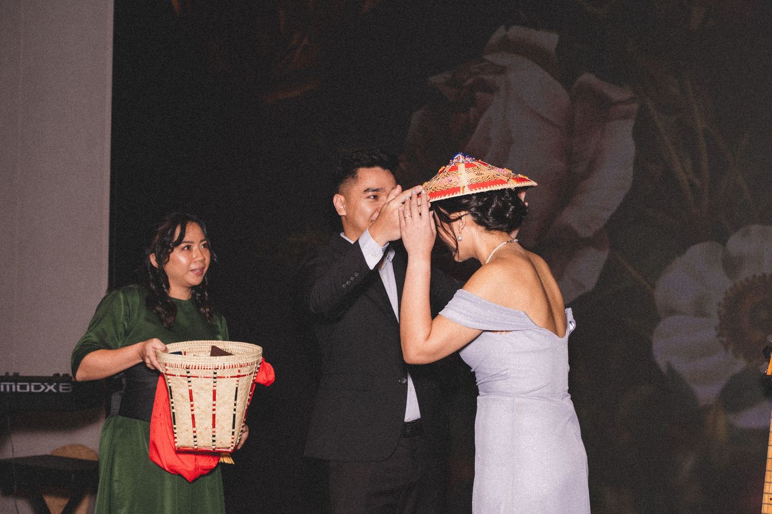 An elegant reception moment captures figures during a wedding celebration against a dark backdrop.