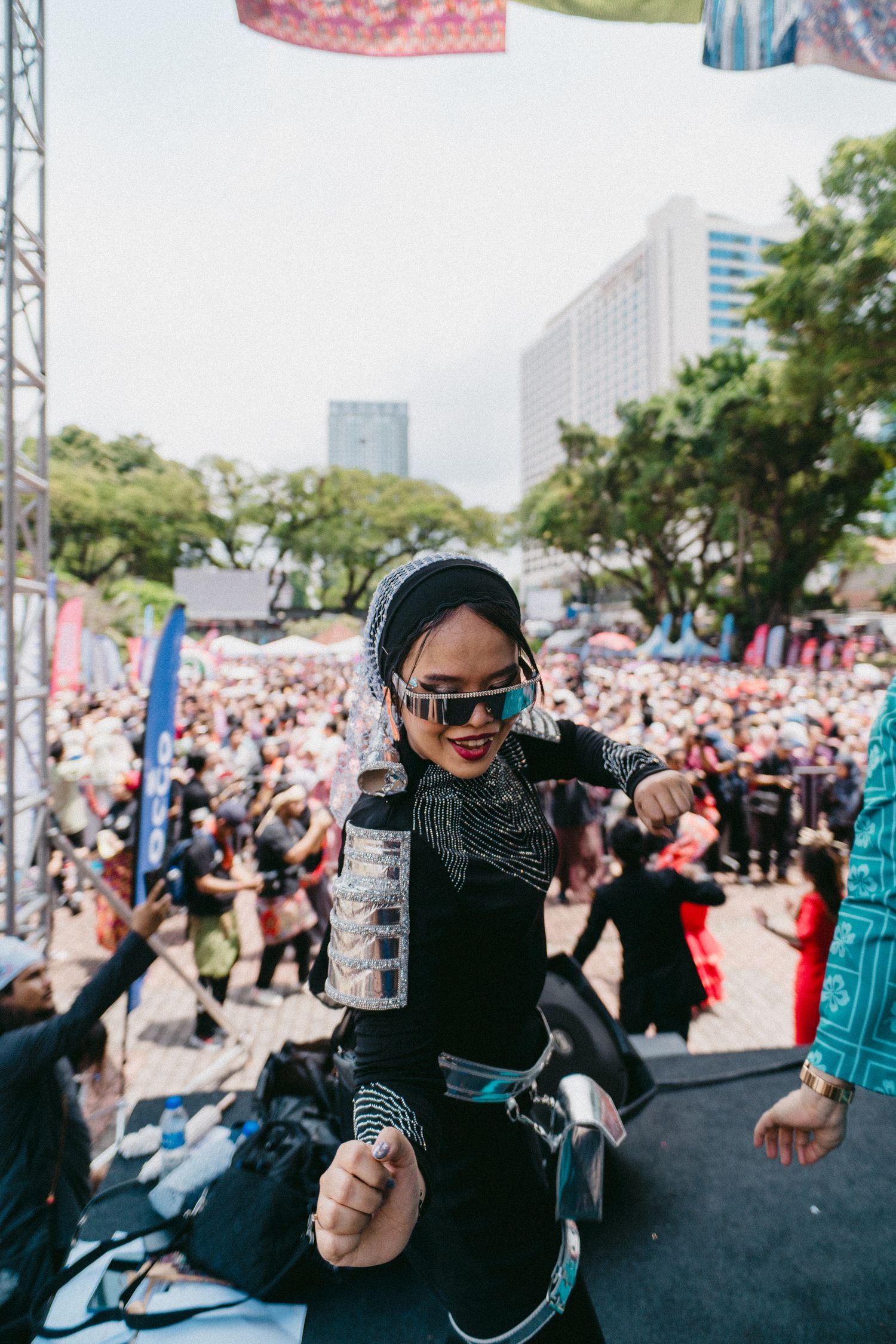 Performer in black outfit with sunglasses on outdoor festival stage.