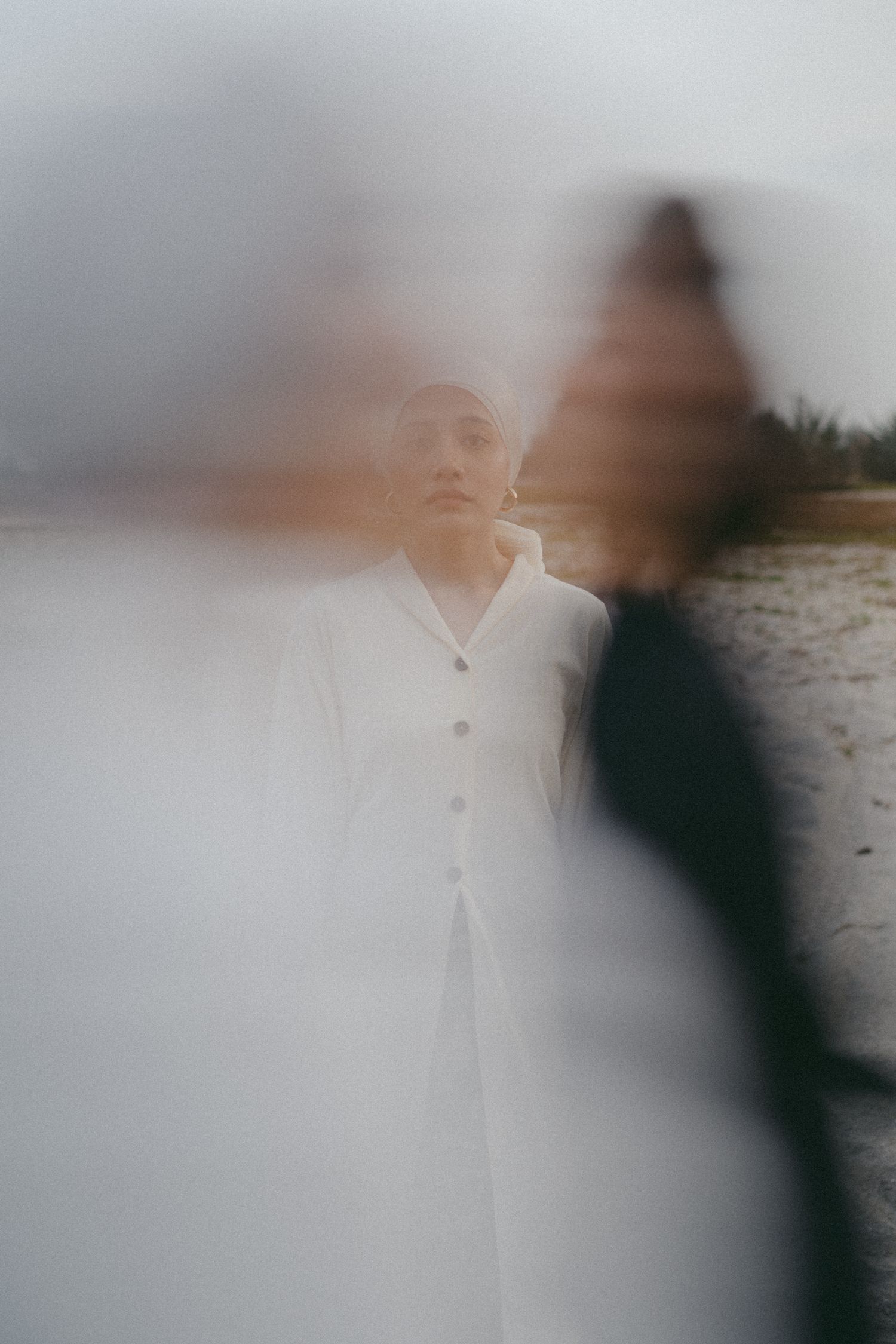 Artistic blurred portrait in white clothing with dreamy atmospheric effect.