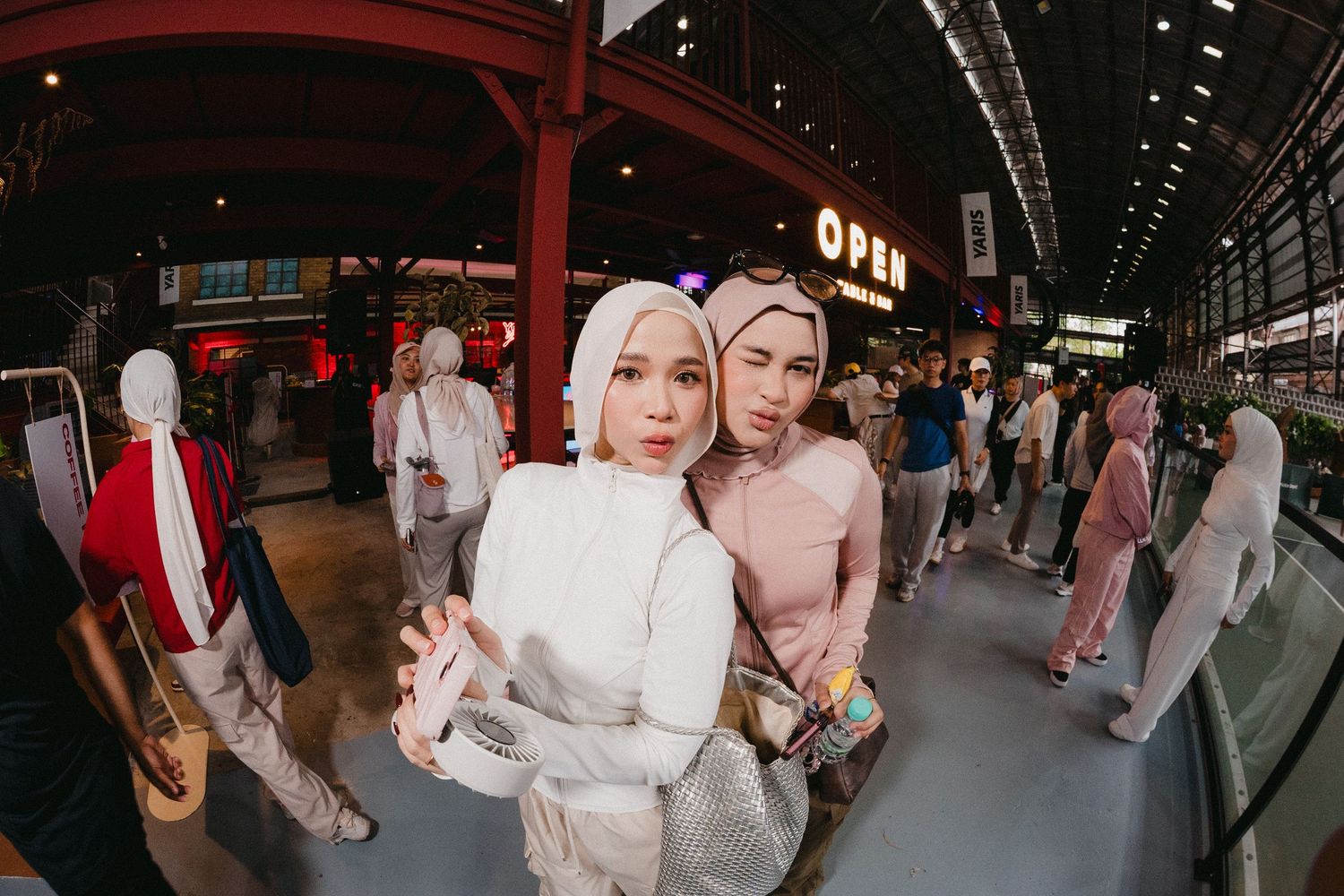 People in traditional clothing walk through a covered shopping arcade with red lanterns overhead in Japan.