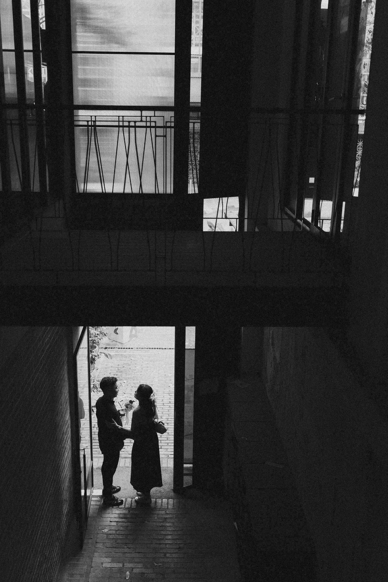 Dramatic silhouette of two people in a dark hallway framed by architectural elements.