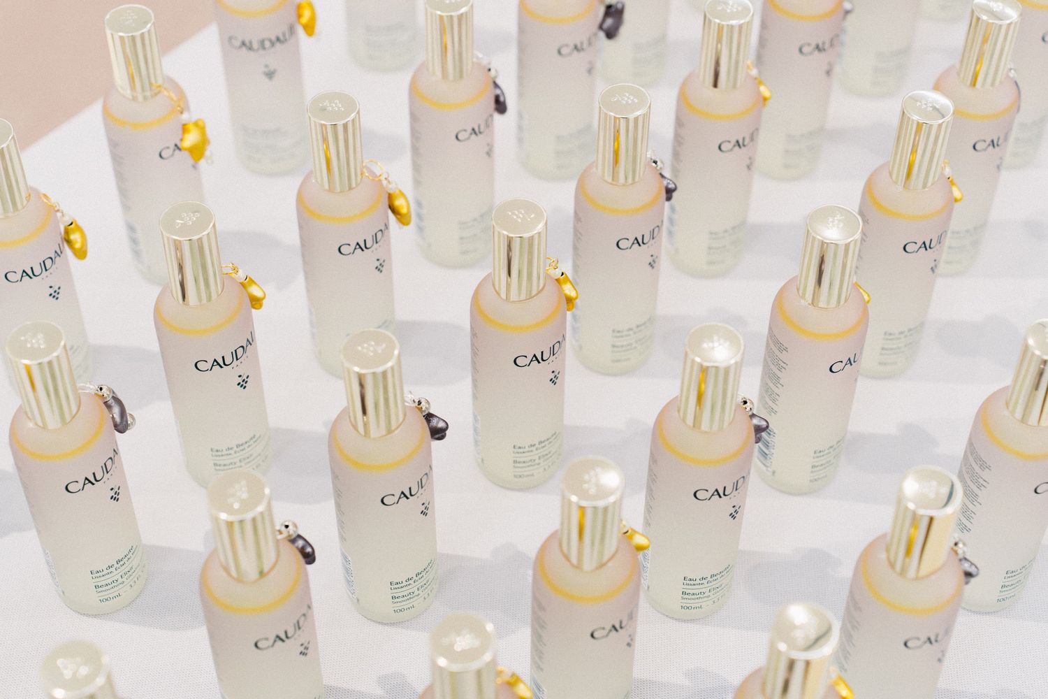 Organized display of identical skincare bottles with gold caps in neat rows.
